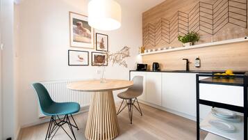 Una cocina moderna con un respuesto de madera en diseño espiga, una mesa redonda de madera, dos sillas y una lámpara colgante.