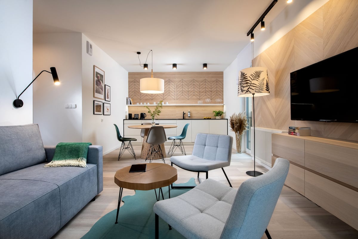 Una sala moderna con un sofá, sillones, una mesa de centro y una zona de comedor con una mesa y sillas.