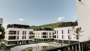 Een modern appartementencomplex met meerdere gebouwen, een centrale binnenplaats en een kleine vijver.