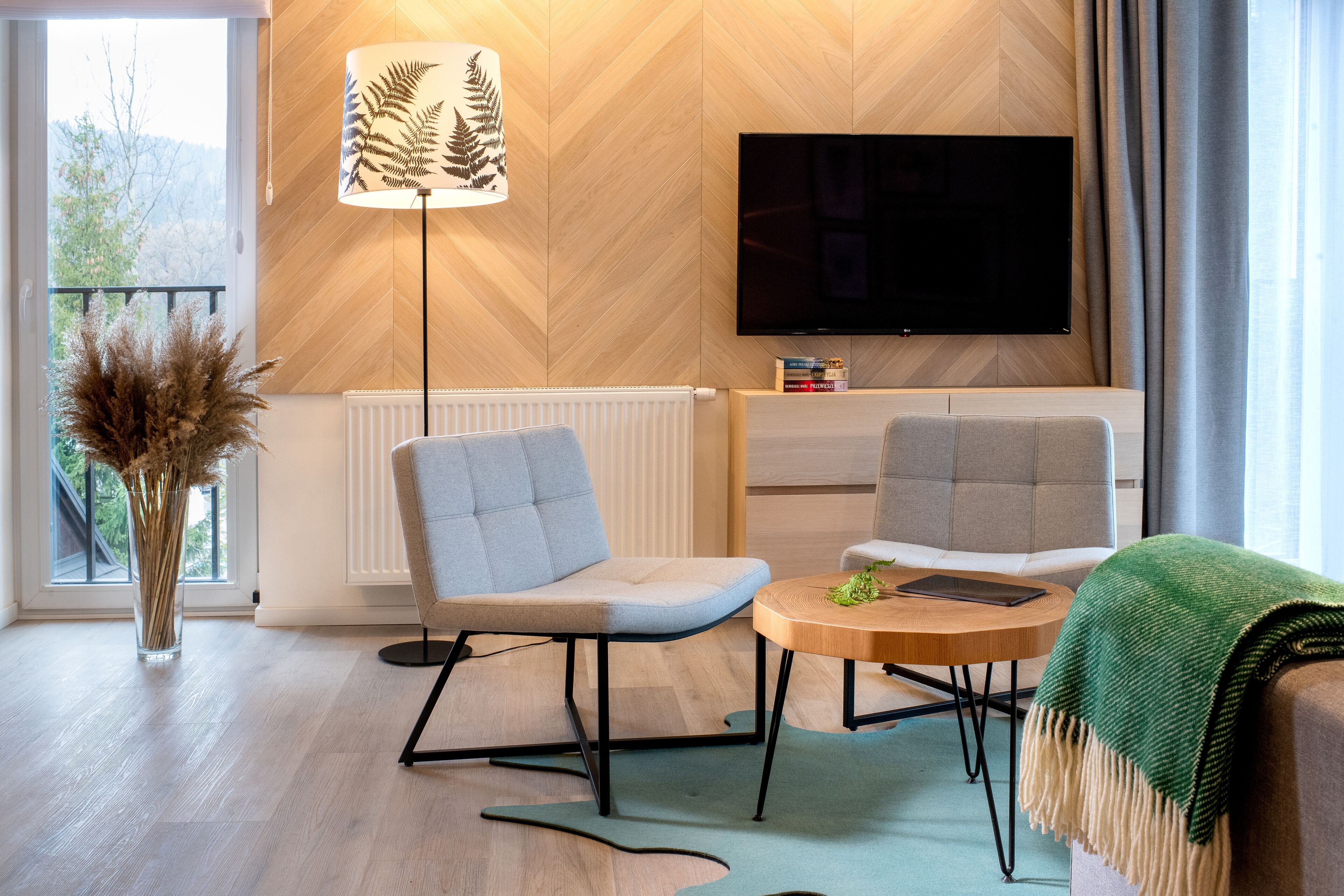 A modern living room with a sofa, chairs, a coffee table, a TV, and a radiator.