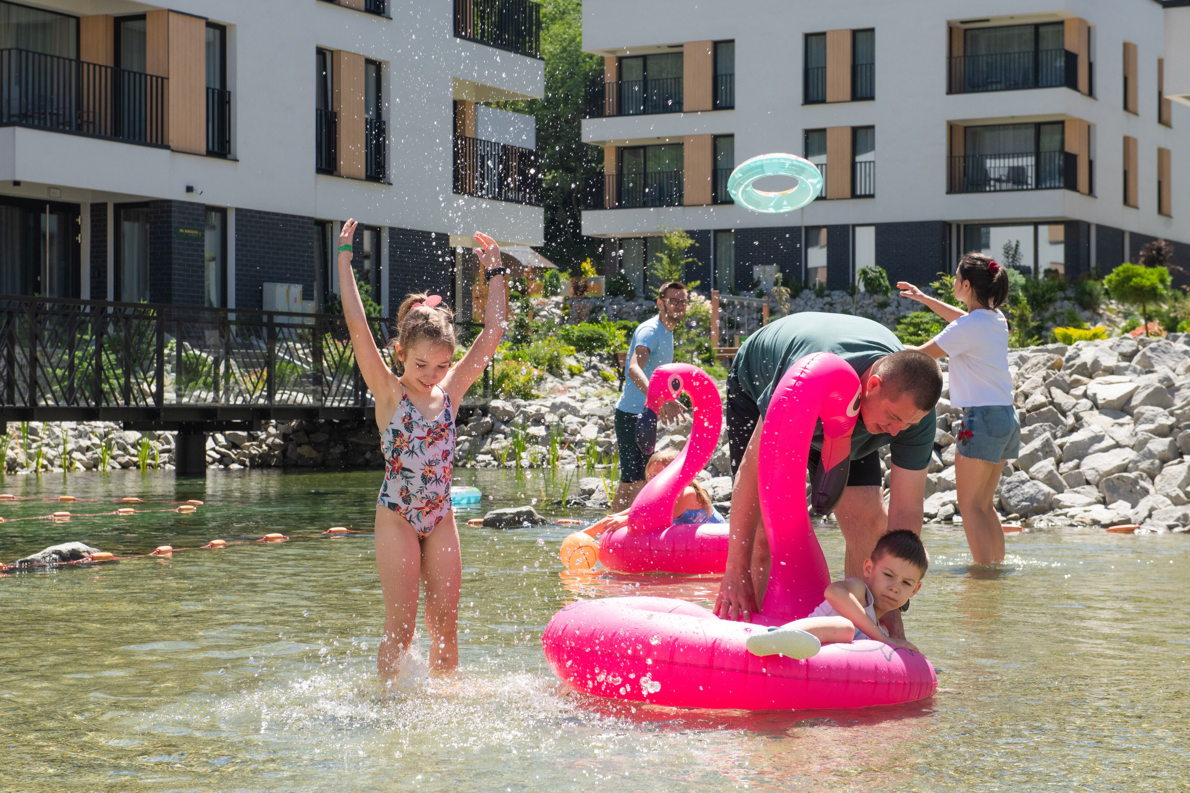 Un espace piscine agrémenté de flamants roses gonflables, où les gens se détendent et profitent de l’eau.