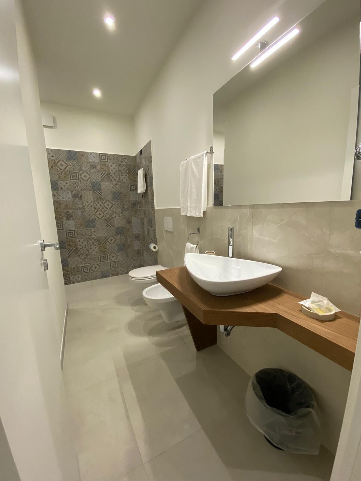 Ein modernes Badezimmer mit einem großen Waschbecken, einem Spiegel und einer Duschkabine.
