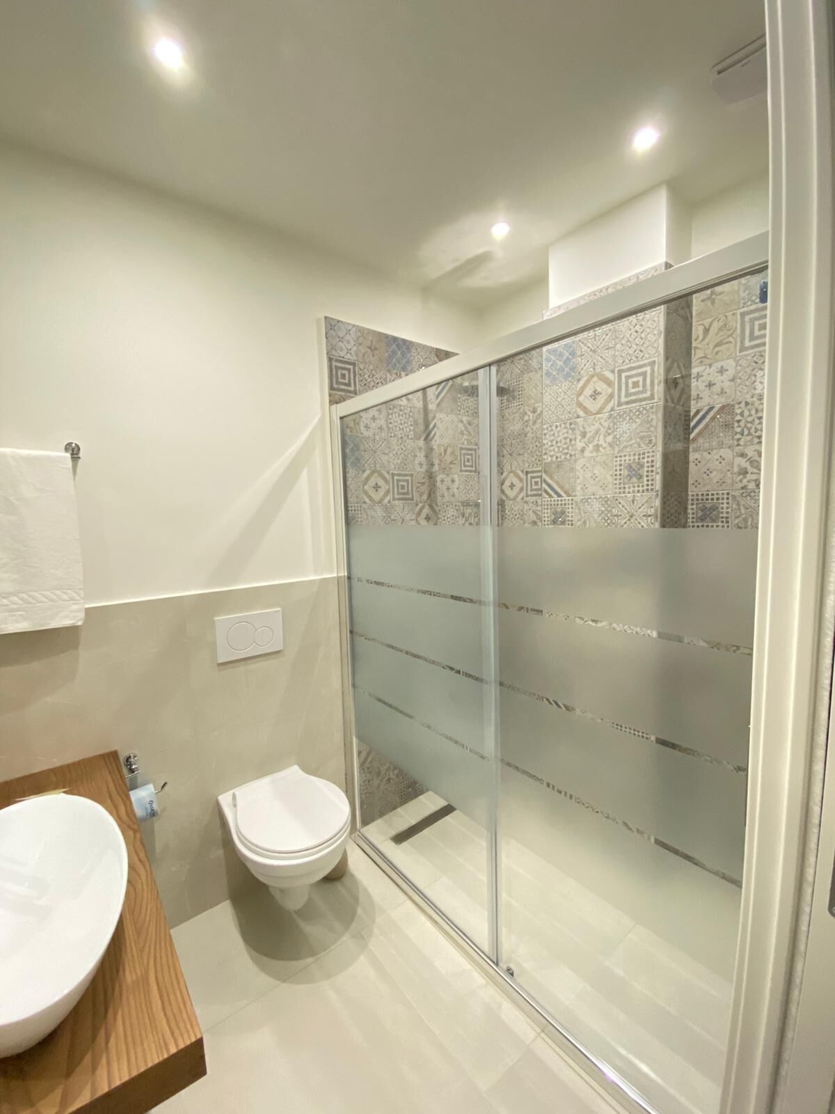 Ein modernes Badezimmer mit einer begehbaren Glasdusche, einem Holzbadezimmermöbel und einer weißen Toilette.