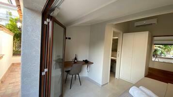 A hotel room with a bed, a desk, and a chair. There is a window with a view of the outside.