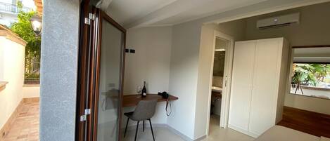Habitación de hotel con cama, escritorio y silla. Ventana con vistas al exterior.