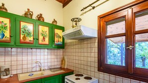 A kitchen with green cabinets, a white stove, and a window with a view of greenery. - The Fairytale House Seaside Retreat (Messini)