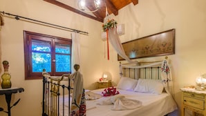 A bedroom with a bed, a nightstand, a table, and a window. - The Fairytale House Seaside Retreat (Messini)