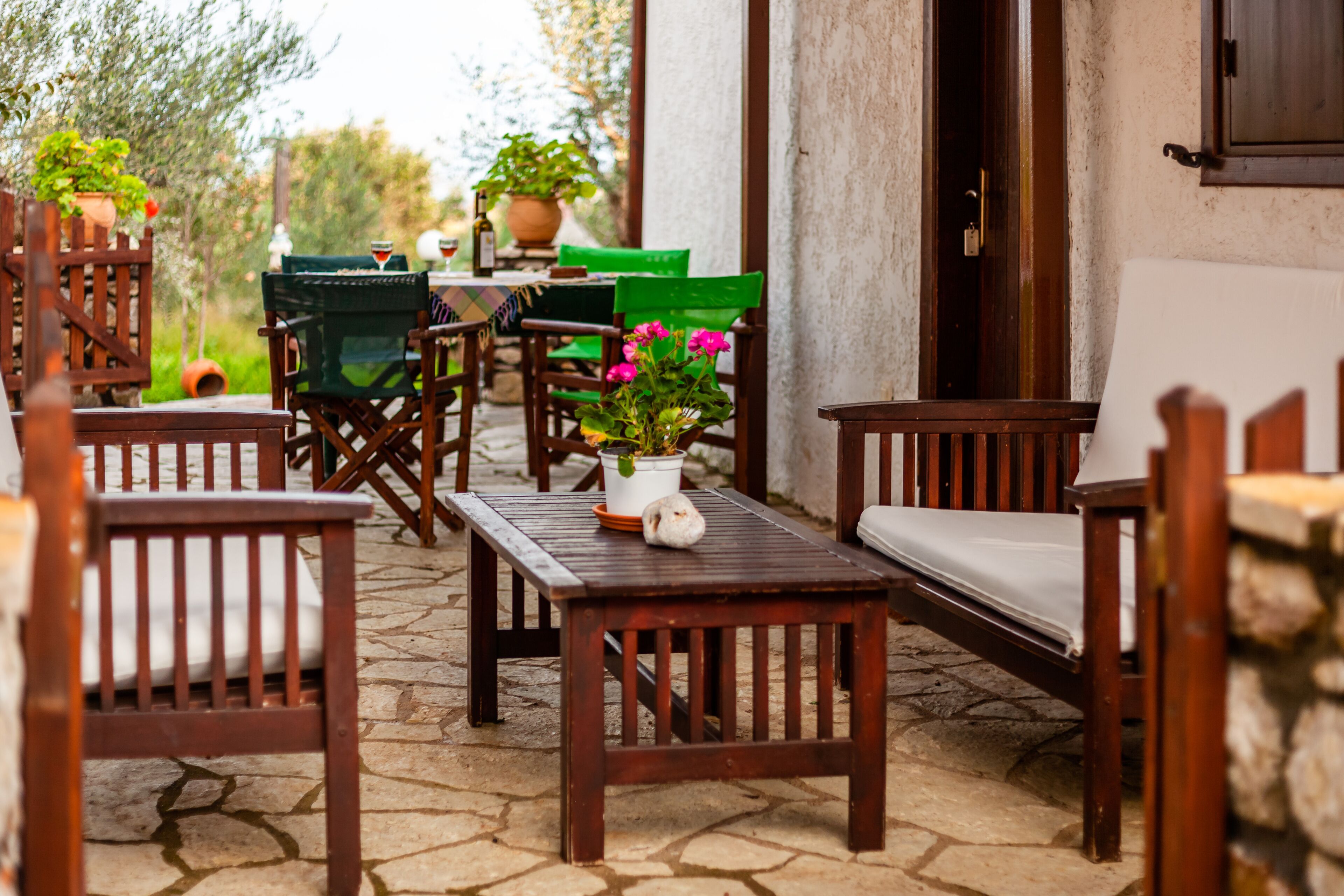 Une terrasse extérieure avec des meubles en bois, une table agrémentée d’une plante en pot et un sol en pierre.