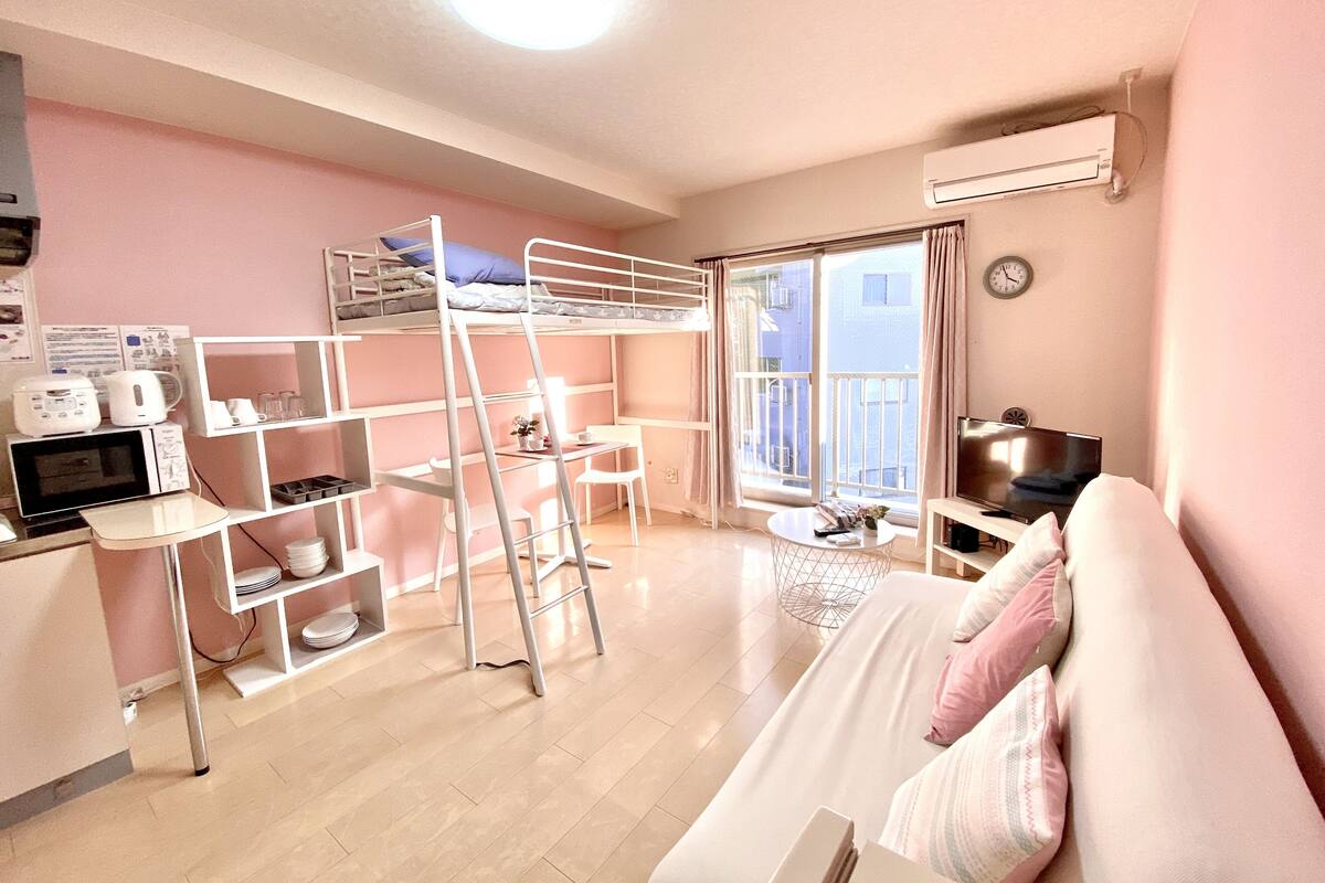A compact room with bunk beds, a kitchenette, a dining area, and a large window.