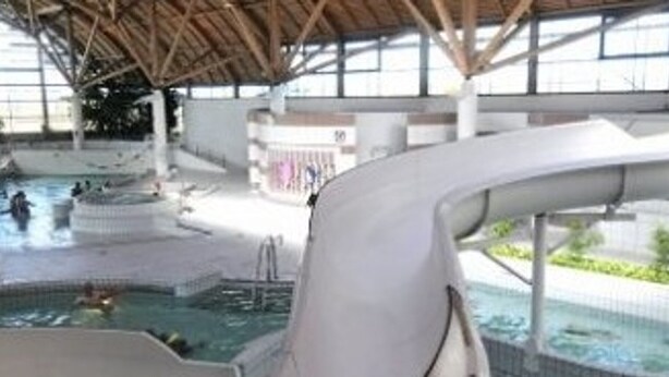 Une piscine intérieure avec un toboggan, un toit abrité et une vue dégagée sur les environs.