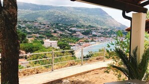 A terrace with a view of a coastal town, a table, and a chair. - Hotel Marina del Capo (Ricadi)