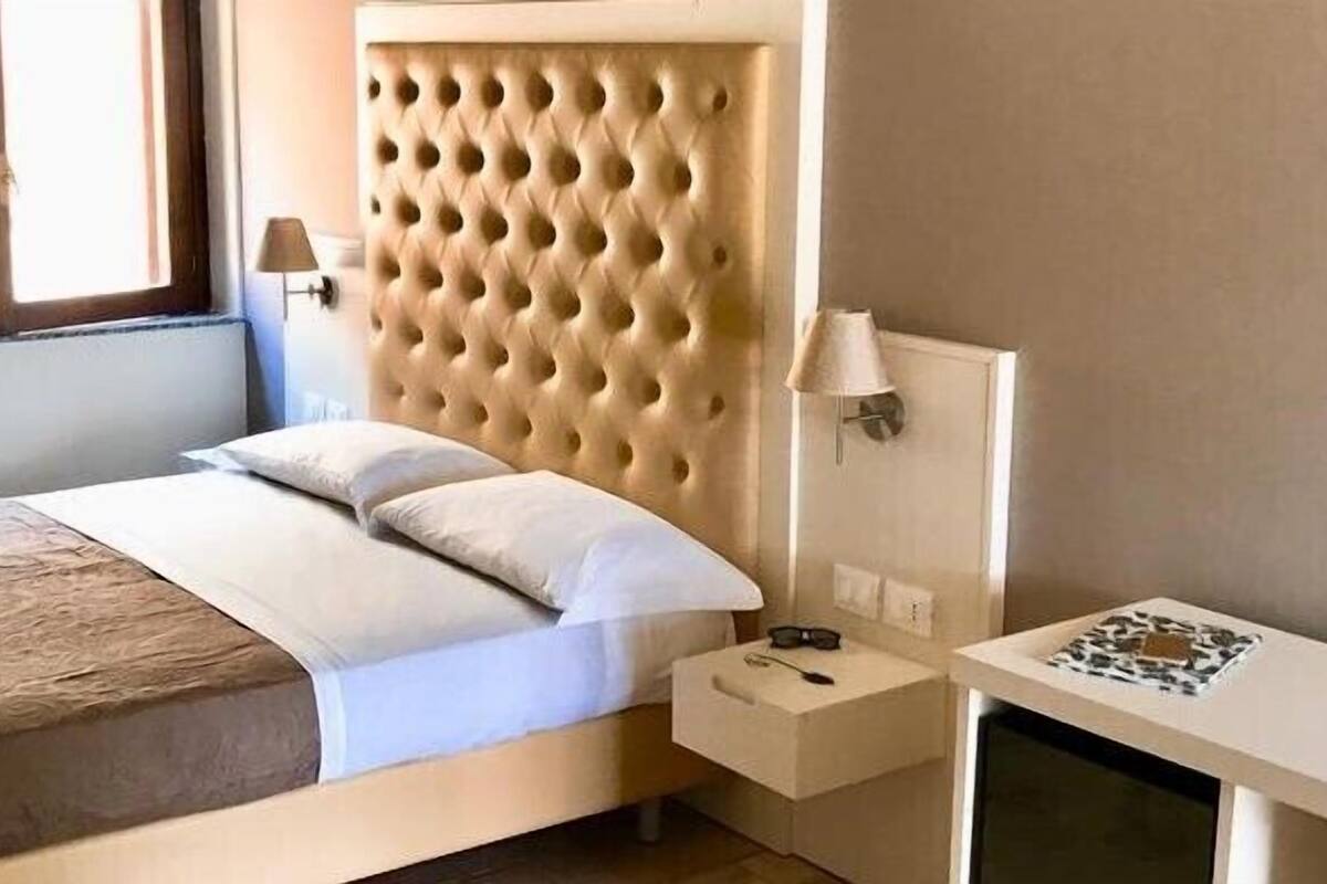A bedroom with a bed, bedside table, lamp, and a small desk with a lamp.