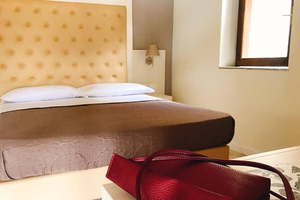 A bed with a tufted headboard, a bedside table, and a lamp.