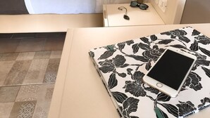 A neatly made bed with white bedding, a bedside table with a pair of sunglasses and a phone on it, and a patterned notebook or folder. - Hotel Marina del Capo (Ricadi)