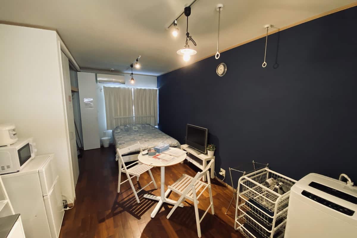 A compact room with a bed, a small table with a TV, a microwave, and a refrigerator.