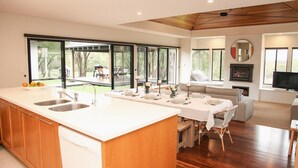 A modern kitchen with a large island, a dining area with a long table, and a cozy seating area with a fireplace.