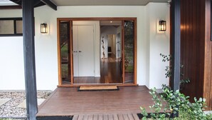 A wooden deck leading to a sliding glass door entrance with a doormat.