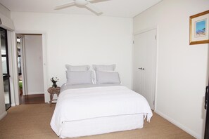 A bedroom with a large bed, a ceiling fan, and a door leading to another room. - Green Park - resort style rural retreat (Quindalup)