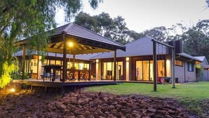 A modern house with a covered patio, large windows, and a well-maintained lawn.