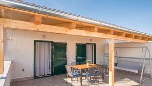 A covered outdoor area with a wooden table and chairs, a bench, and a swing set. - Apartments Anita Summer (Vodice)