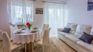 Un coin repas avec une table ronde, des chaises blanches et un canapé beige.