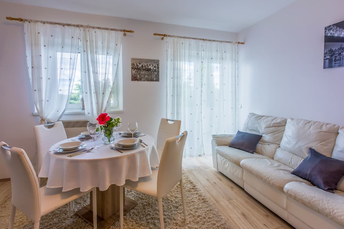 A dining area with a round table, white chairs, and a beige sofa.