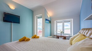 Une chambre à coucher avec un lit, un téléviseur à écran plat, une fenêtre donnant sur un beau paysage et une petite table avec une plante.