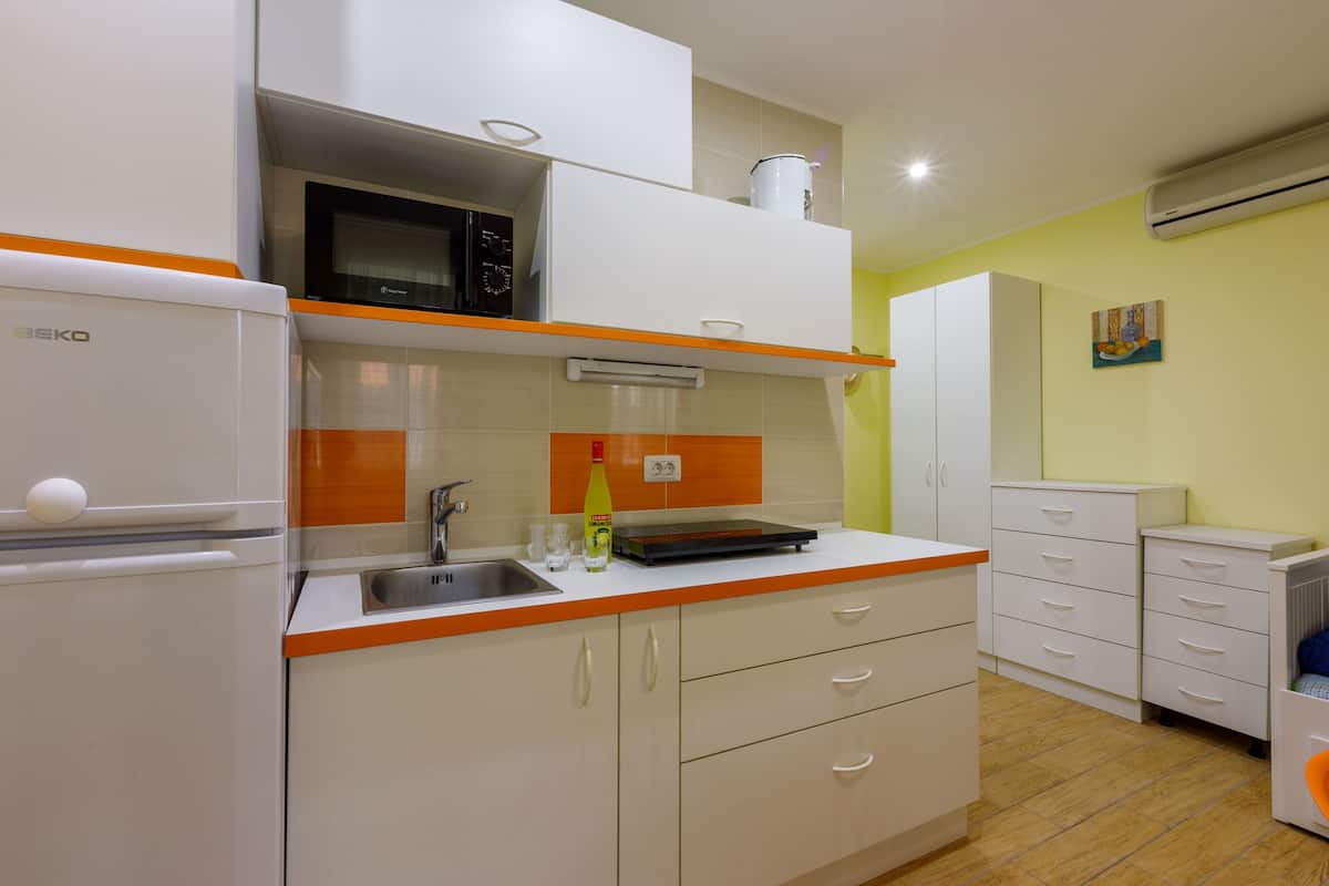 A compact kitchen with white cabinets, a microwave, a sink, and a small countertop.
