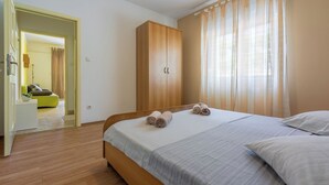 Une chambre à coucher avec un lit en bois, une armoire et une salle de bain visible à travers une porte ouverte.