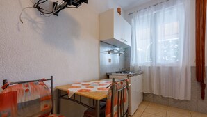 A compact kitchen with a dining area, including a table with a patterned tablecloth and a sofa with cushions. - Apartments Lory (Dramalj)
