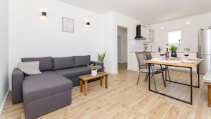 A modern living room with a grey sofa, a wooden coffee table, and a dining area with a table set for two. - Villa Dupla Kanica (Kanica)
