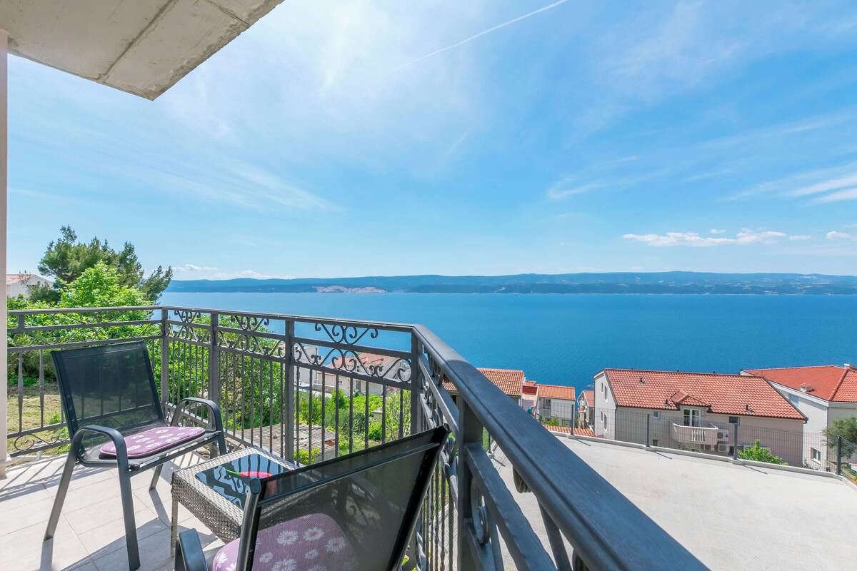 A balcony with a view of a body of water and distant mountains.