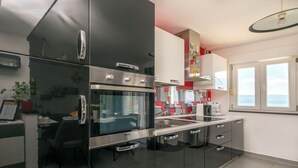 Una cocina moderna con electrodomésticos de acero inoxidable, una zona de comedor con una silla negra y una ventana con vistas.