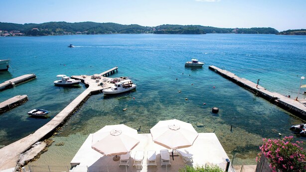 Un port de plaisance avec des bateaux amarrés, une eau claire et des parasols pour se protéger du soleil.