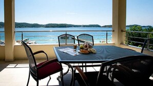 Un balcon avec une table préparée pour le petit-déjeuner, donnant sur un plan d’eau et des collines.