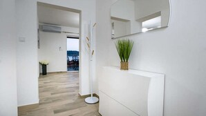 Un couloir moderne avec un plancher en bois, un grand miroir blanc fixé au mur et une petite plante en pot.