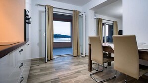 Une chambre d’hôtel avec un plancher en bois, un bureau avec une chaise, un lit et un balcon avec des rideaux.