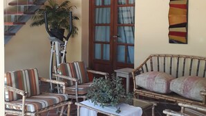 Ein Zimmer mit Treppe, Korbmöbeln, einer Kandelaber und einer Tür mit Glasfeldern.