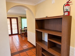 A hallway with a wooden cabinet, a fire extinguisher, and a dining area with a table and chairs. - Family House for 6 People (Salta)