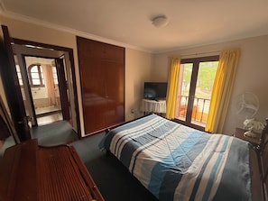 A bedroom with a bed, a television, a fan, and a view of the outdoors through a window. - Family House for 6 People (Salta)