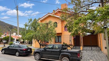 Un barrio residencial con una casa de techo de tejas, un camino de entrada pavimentado y una camioneta negra estacionada.