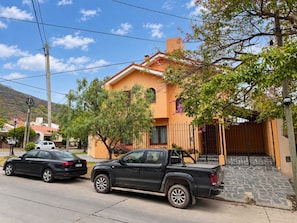 A residential area with a house featuring a tiled roof, a paved driveway, and a parked black pickup truck. - Family House for 6 People (Salta)