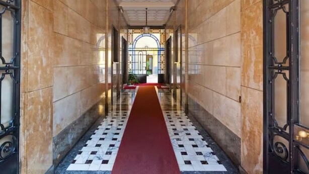 Un couloir doté d’une moquette rouge, d’un sol carrelé et de grilles en métal décoratives.