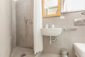 A bathroom with a shower, a sink, a mirror, and a toilet. - Apartment with terrace (Milano)