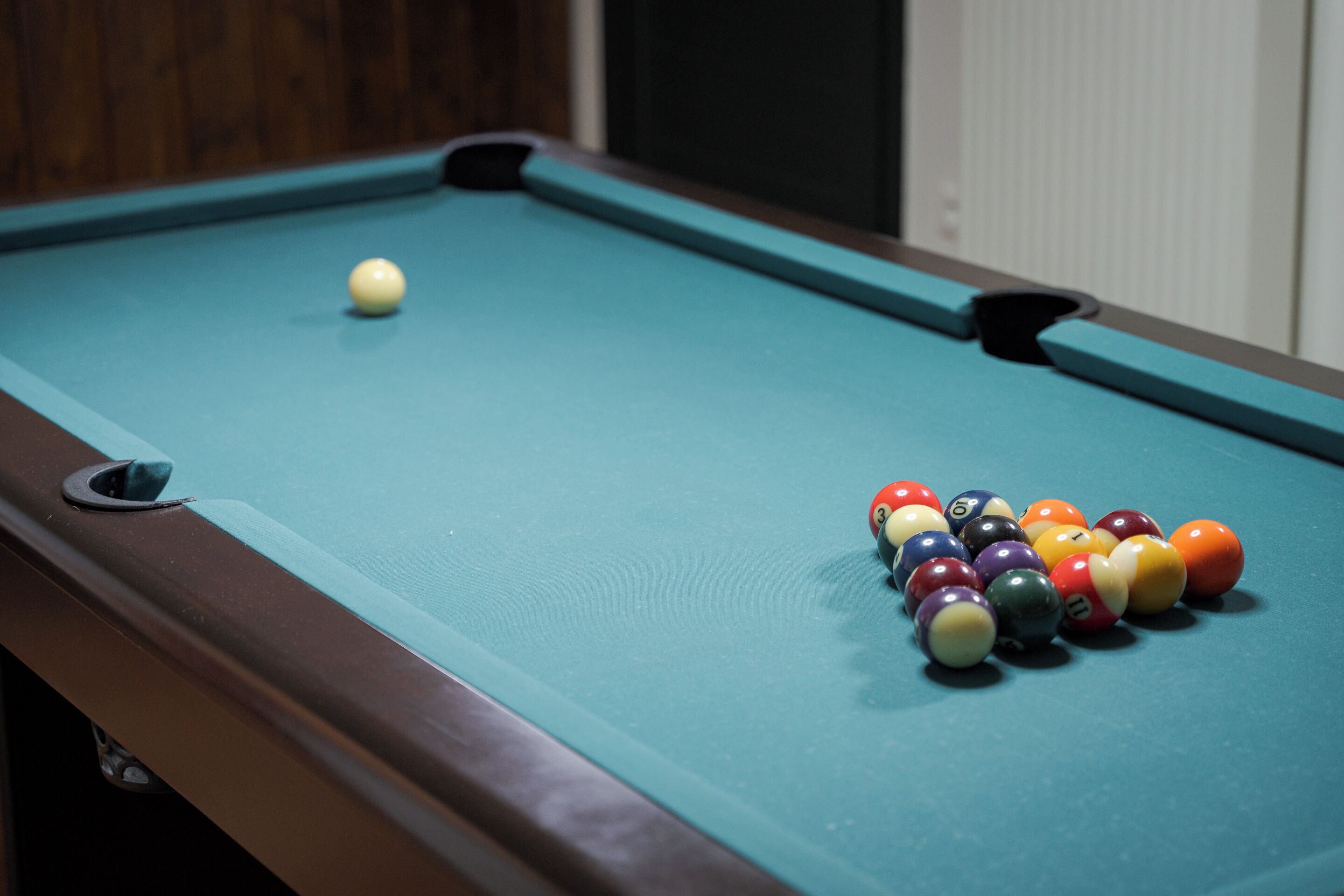 Une table de billard recouverte d’un drap vert et sur laquelle les billes sont disposées en forme de triangle.
