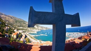 Una gran estructura en forma de cruz con vistas a un pueblo costero y al mar.