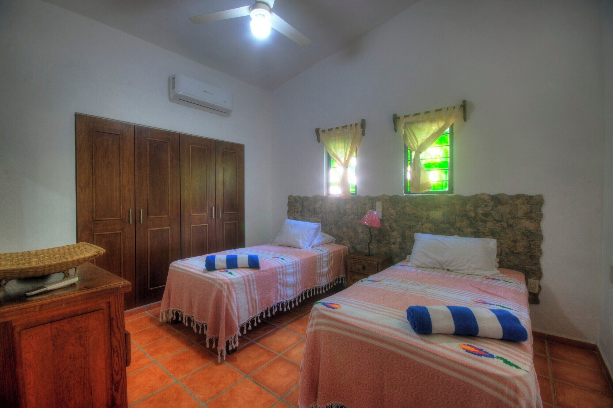 A bedroom with two beds, a wardrobe, a small table, and a ceiling fan.