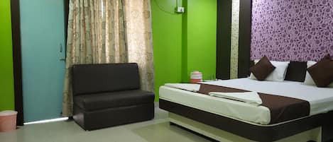 A room with a bed, a sofa, a curtain, and a wall with a floral pattern.