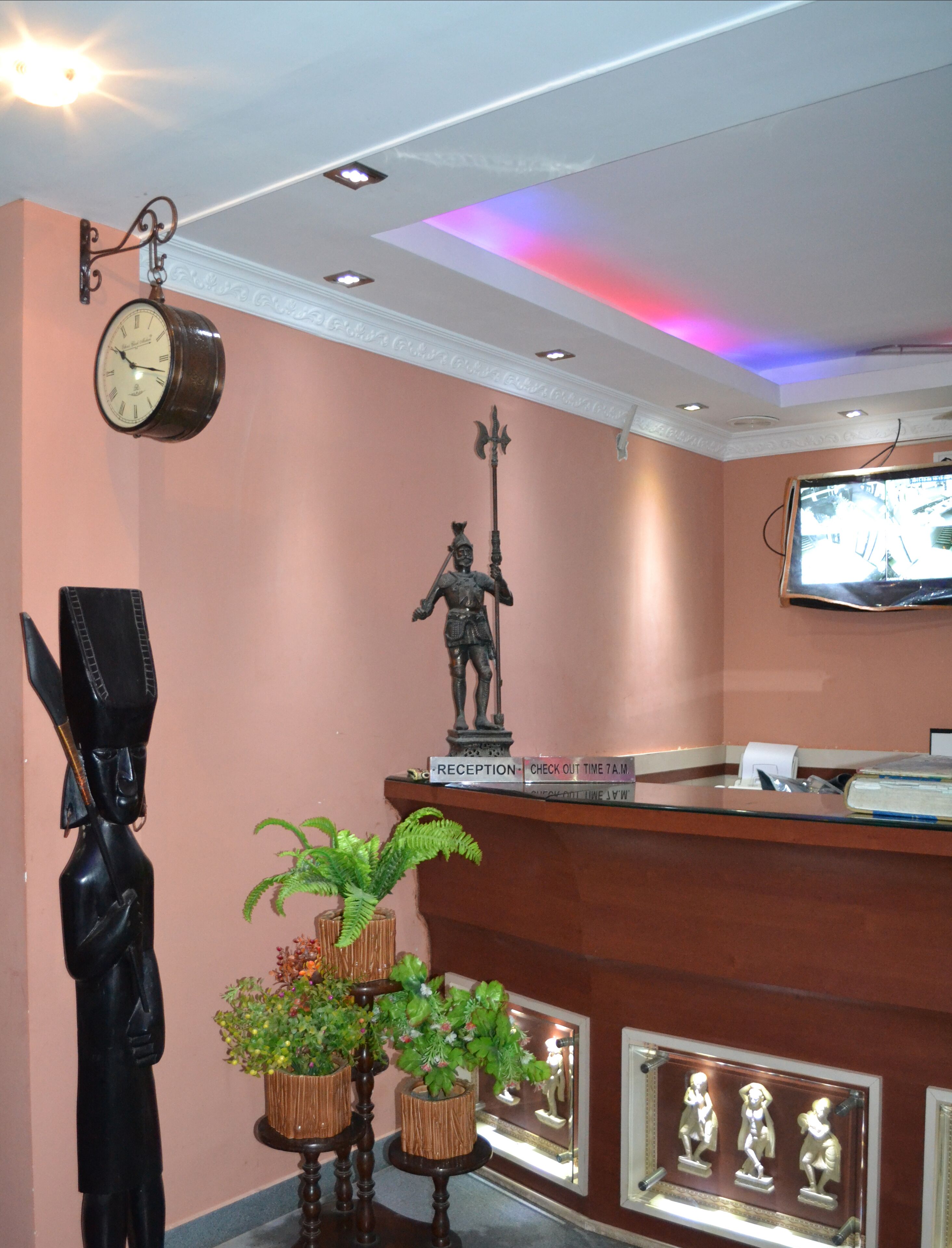 A reception desk with a clock, a statue, and a television.