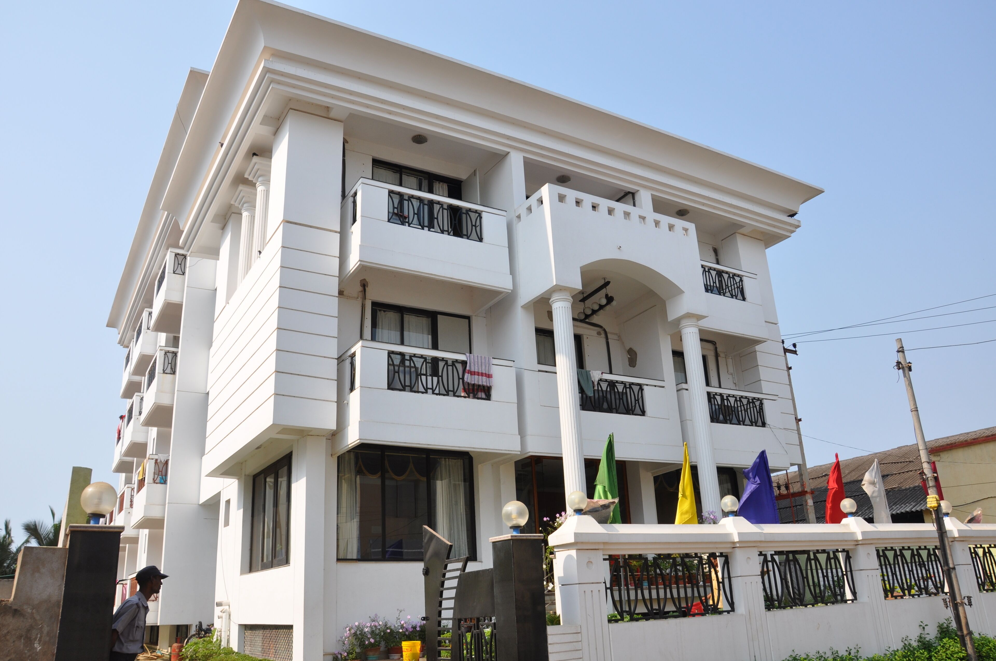 A multi-story building with balconies, a central entrance, and a flag display.